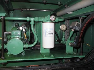 Cette photo représente un système de filtration basse pression sur le retour d’une unité hydraulique dont le manomètre différentiel est hors d’usage. De plus, nous sommes en 2012 et la date inscrite sur le filtre est le 13-02-2008, ce qui indique que le filtre n’a pas été changé depuis quatre (4) ans. Considérant le contexte opérationnel de l’équipement, le remplacement annuel de la cartouche filtrante est recommandé. Malgré cela, on doit effectuer une vérification visuelle mensuelle de l’aiguille du manomètre différentiel afin de déceler une problématique potentielle entre les changements de filtre. Comme le manomètre est hors d’usage, il est impossible d’effectuer cette importante vérification. Rappelons qu’un manomètre différentiel nous permet de visualiser le degré de colmatage de l’élément filtrant et que des inspections visuelles régulières permettent de vérifier la vitesse à laquelle le colmatage s’effectue.
